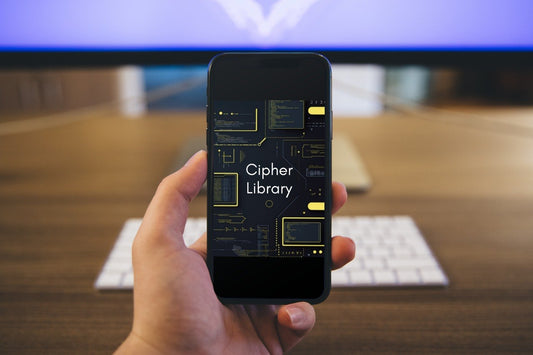 Hand holding a smartphone with 'Cipher Library' app displayed on a blurred office desk background